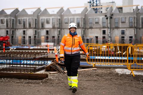 HLM-landmåler går hen over en byggeplads foran rækkehuse i råhus