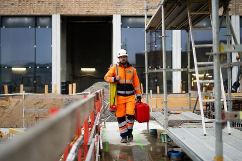 HLM-landmåler på byggepladsen i skumringen med instrumentkasse i hånden